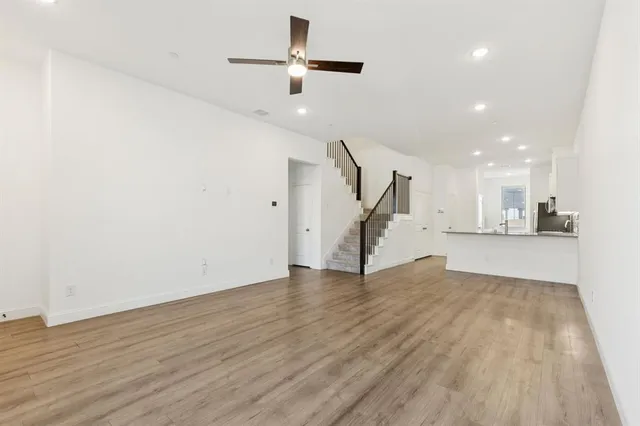 a view of an empty room with wooden floor ceiling fan