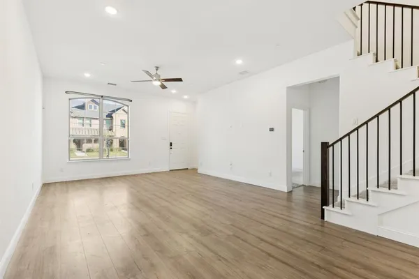 an empty room with wooden floor chandelier fan and windows