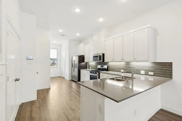 a kitchen with stainless steel appliances granite countertop a sink a stove and refrigerator