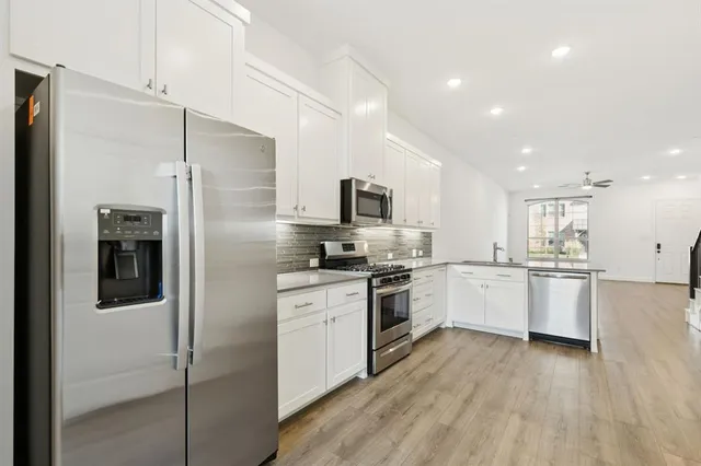 a kitchen with a refrigerator a sink and white cabinets