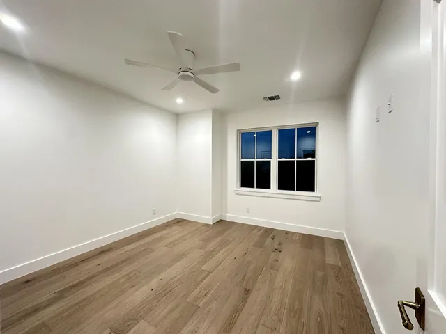 an empty room with wooden floor cabinet and windows