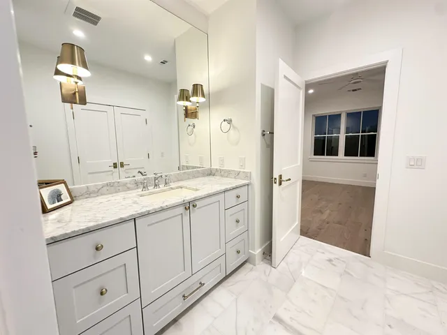 a view of a white house next to a yard with plants and trees