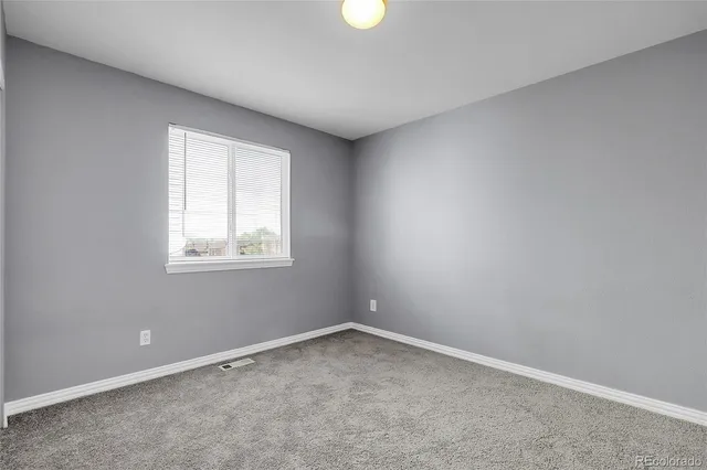 an empty room with chandelier fan and windows