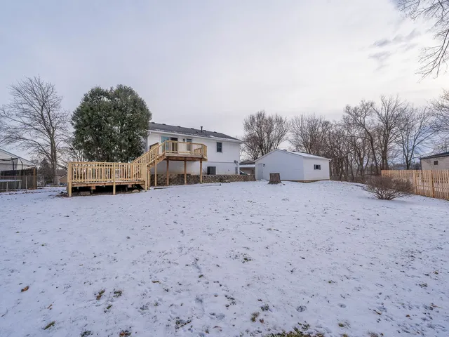 a front view of a house with a yard and covered with snow