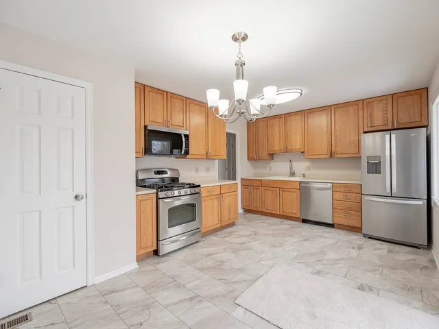 a kitchen with a sink stainless steel appliances and chandelier