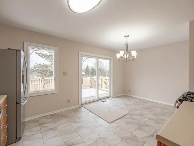 an empty room with chandelier fan and windows