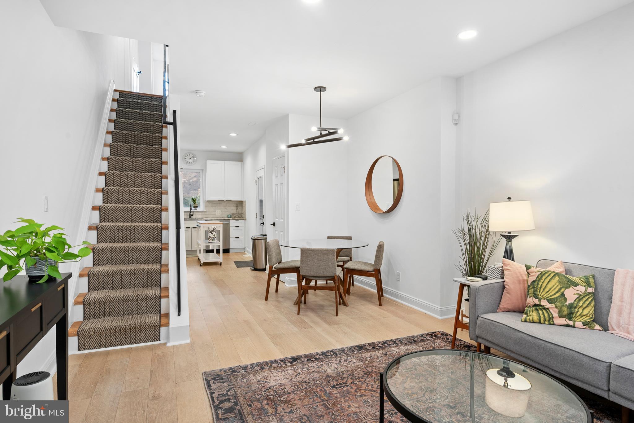a living room with furniture a dining table with wooden floor and potted plants