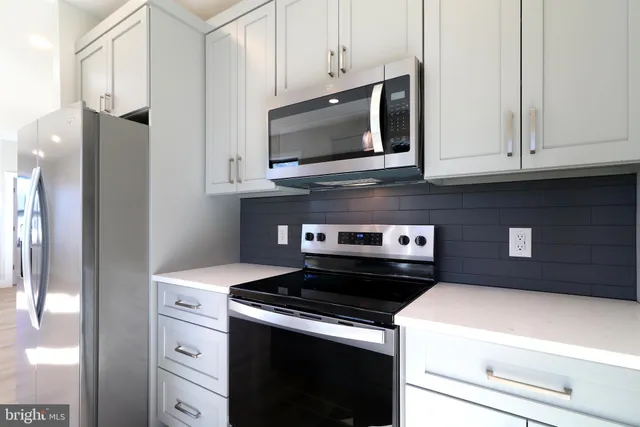 a kitchen with stainless steel appliances granite countertop a refrigerator and a stove top oven