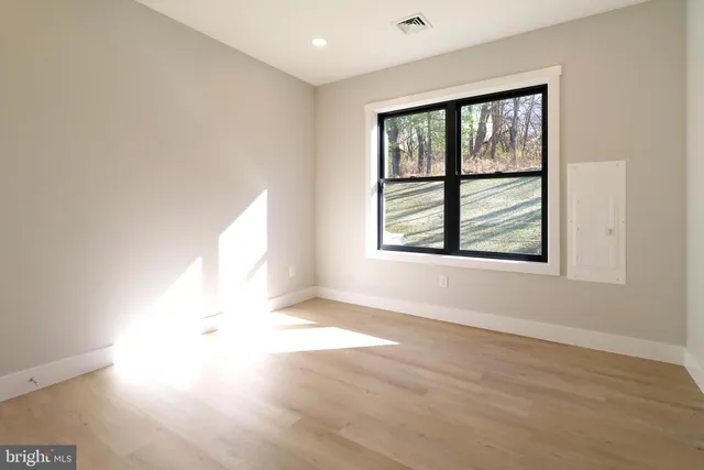 an empty room with wooden floor and windows