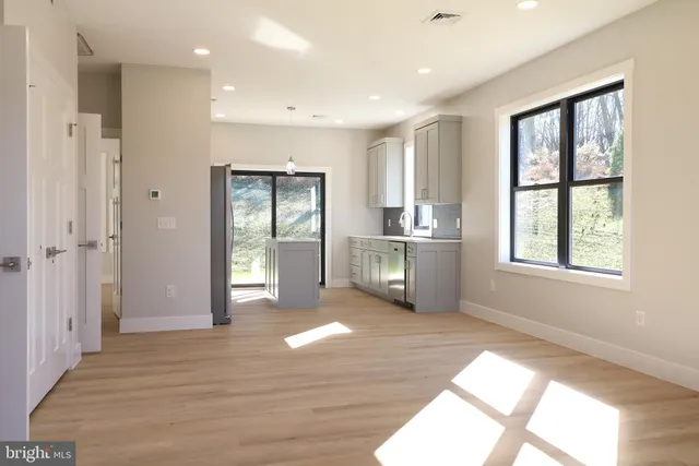 a kitchen with stainless steel appliances granite countertop a refrigerator a sink dishwasher a stove and a dining table with wooden floor