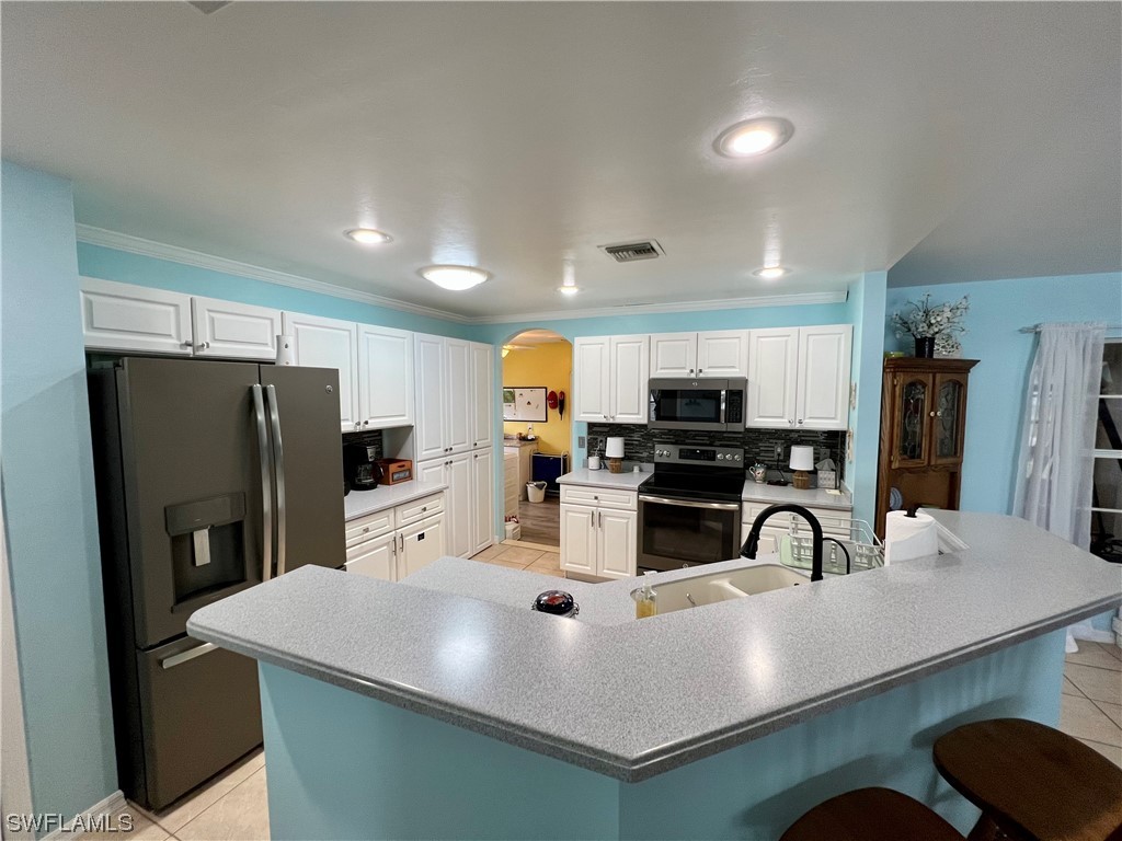 153 Patio Street Lehigh Acres, FL 33974 - Photo 15 of 27 a kitchen with stainless steel appliances a sink a microwave a refrigerator and cabinets