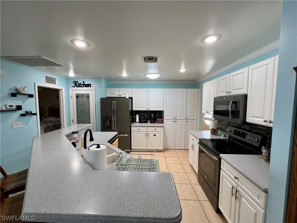 153 Patio Street Lehigh Acres, FL 33974 - Photo 18 of 27 a kitchen with stainless steel appliances granite countertop a sink stove and refrigerator