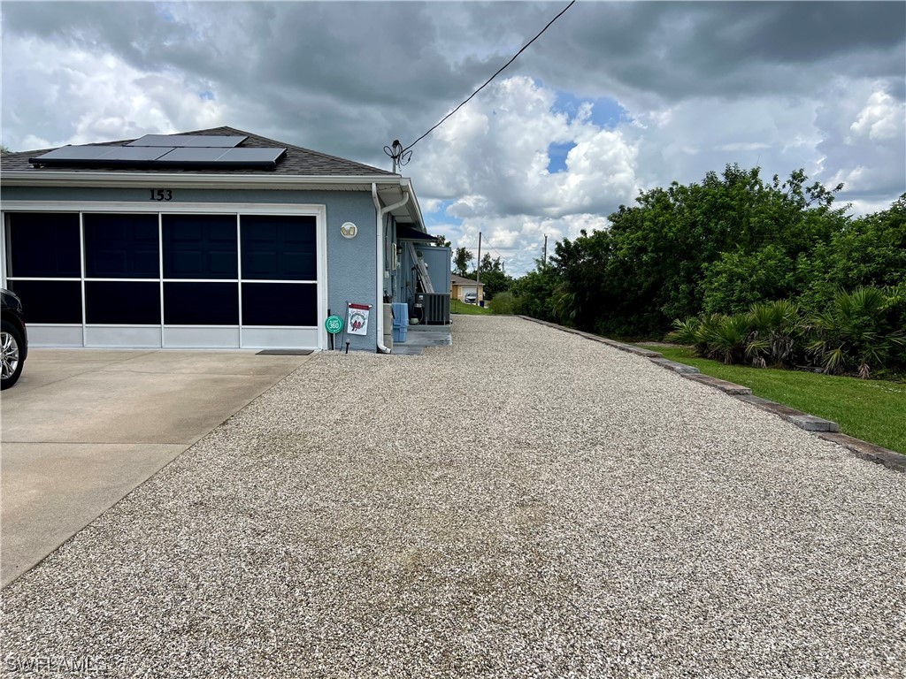 153 Patio Street Lehigh Acres, FL 33974 - Photo 27 of 27 a view of a house with a yard and garage