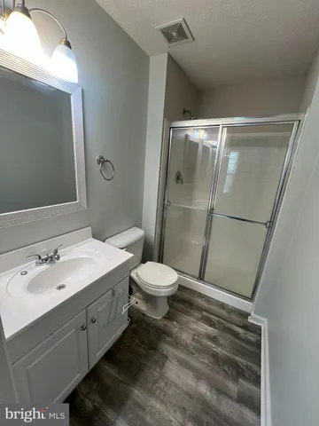 a bathroom with a granite countertop sink toilet a mirror and shower