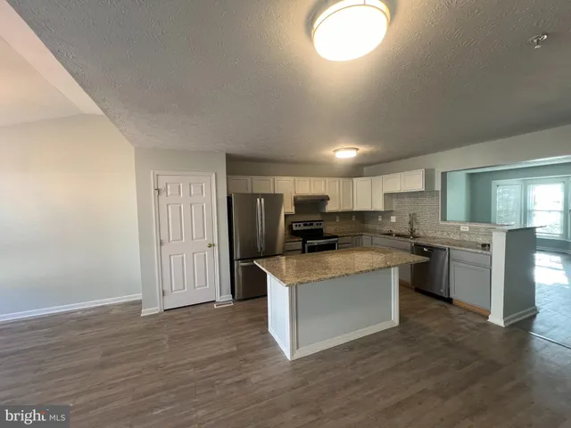 a kitchen with kitchen island sink stove and refrigerator