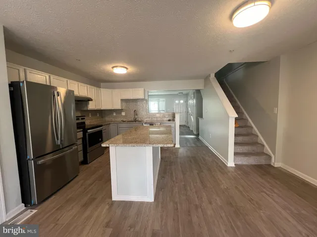 a kitchen with stainless steel appliances a refrigerator and wooden floor