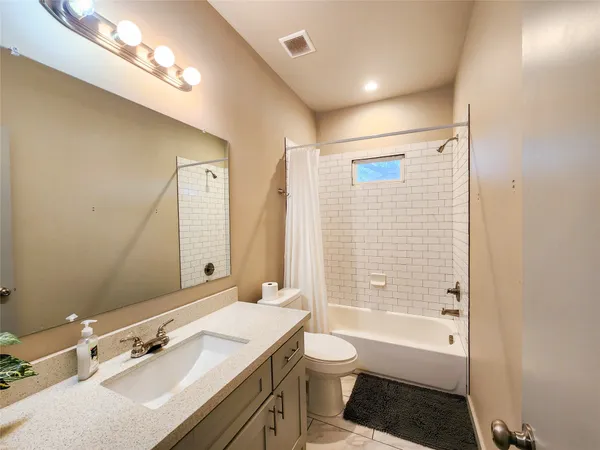 a bathroom with a granite countertop sink a toilet a mirror and shower