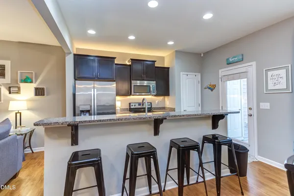 a kitchen with stainless steel appliances a table chairs refrigerator and microwave