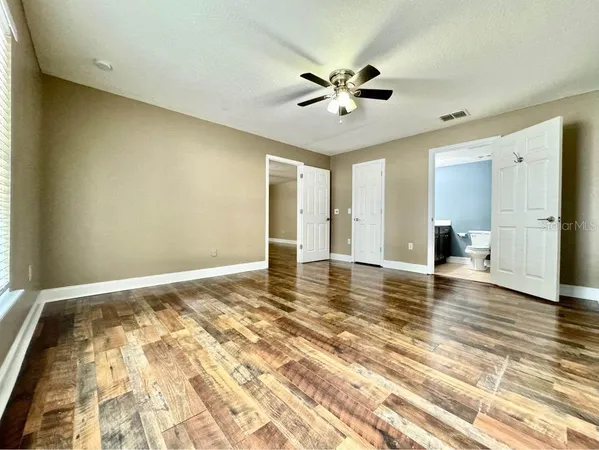 a view of empty room with wooden floor and fan