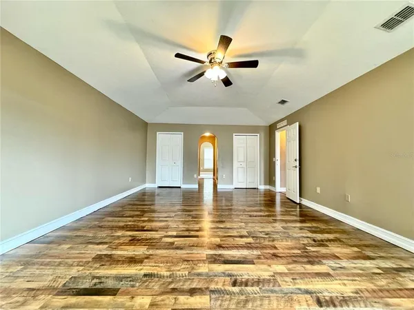 a view of an empty room with window and wooden floor