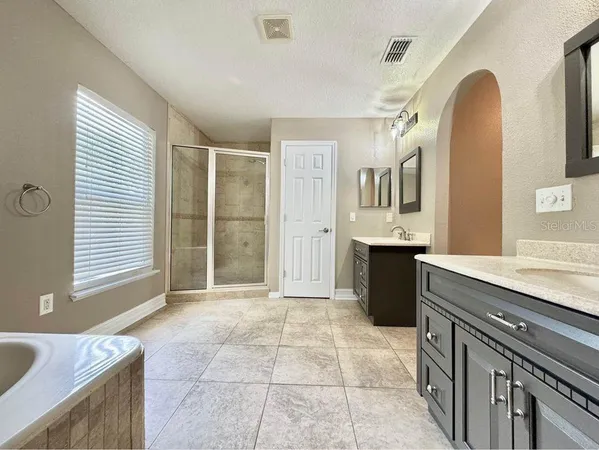 a spacious bathroom with a granite countertop sink a mirror a bathtub and next to a window