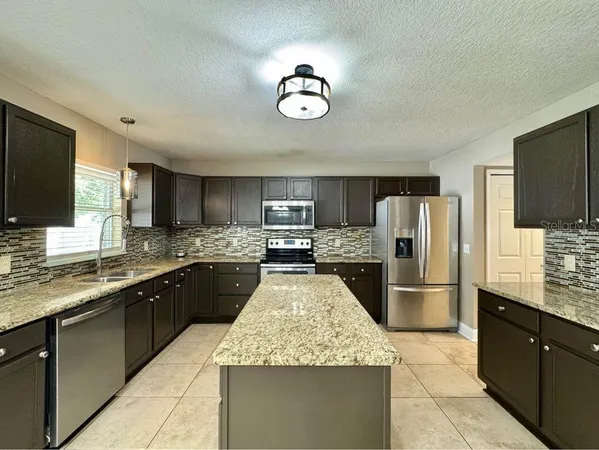 a large kitchen with a large counter top a refrigerator and a sink