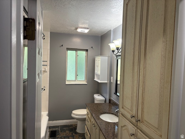 2313 150 East Bountiful, UT 84010 - Photo 22 of 39 Bathroom featuring a built-in vanity with a stone countertop and integrated sink, extensive cabinetry, a wall-mounted light fixture, and textured flooring