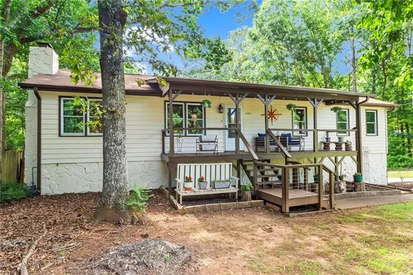 a view of a house with a wooden deck and a forest