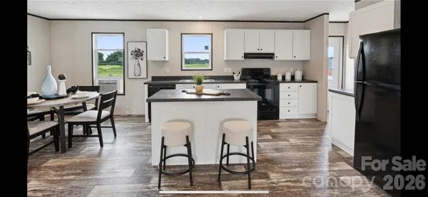 a kitchen with stainless steel appliances a dining table chairs refrigerator and sink