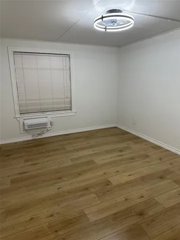 a view of an empty room with wooden floor and cabinet