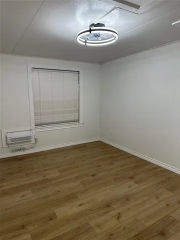 a view of empty room with wooden floor and window