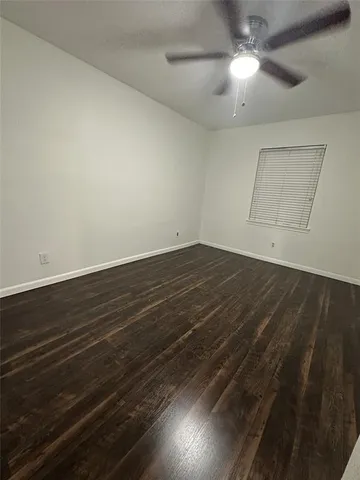 en empty room with wooden floor and fan