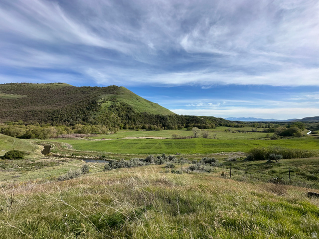 4250 East Cub River Road Preston, ID 83263 - Photo 5 of 18 Expansive natural landscape featuring rolling green hills, a winding stream, distant mountain ranges, vibrant foliage, and open fields