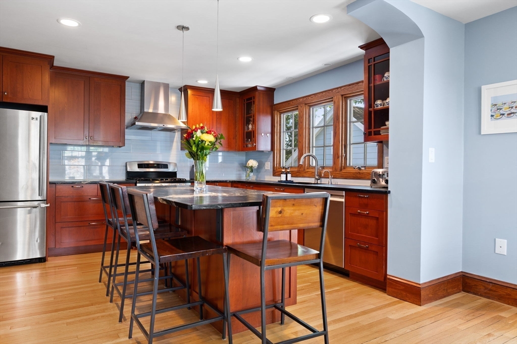 80 Baxter Street Melrose, MA 02176 - Photo 6 of 23 a kitchen with stainless steel appliances granite countertop wooden floor a dining table and chairs