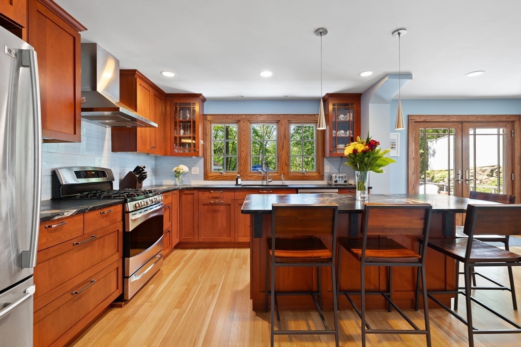 80 Baxter Street Melrose, MA 02176 - Photo 7 of 23 a kitchen with stainless steel appliances granite countertop wooden floor dining table and chairs