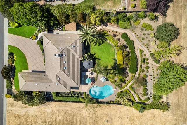 an aerial view of a house with a yard and large trees