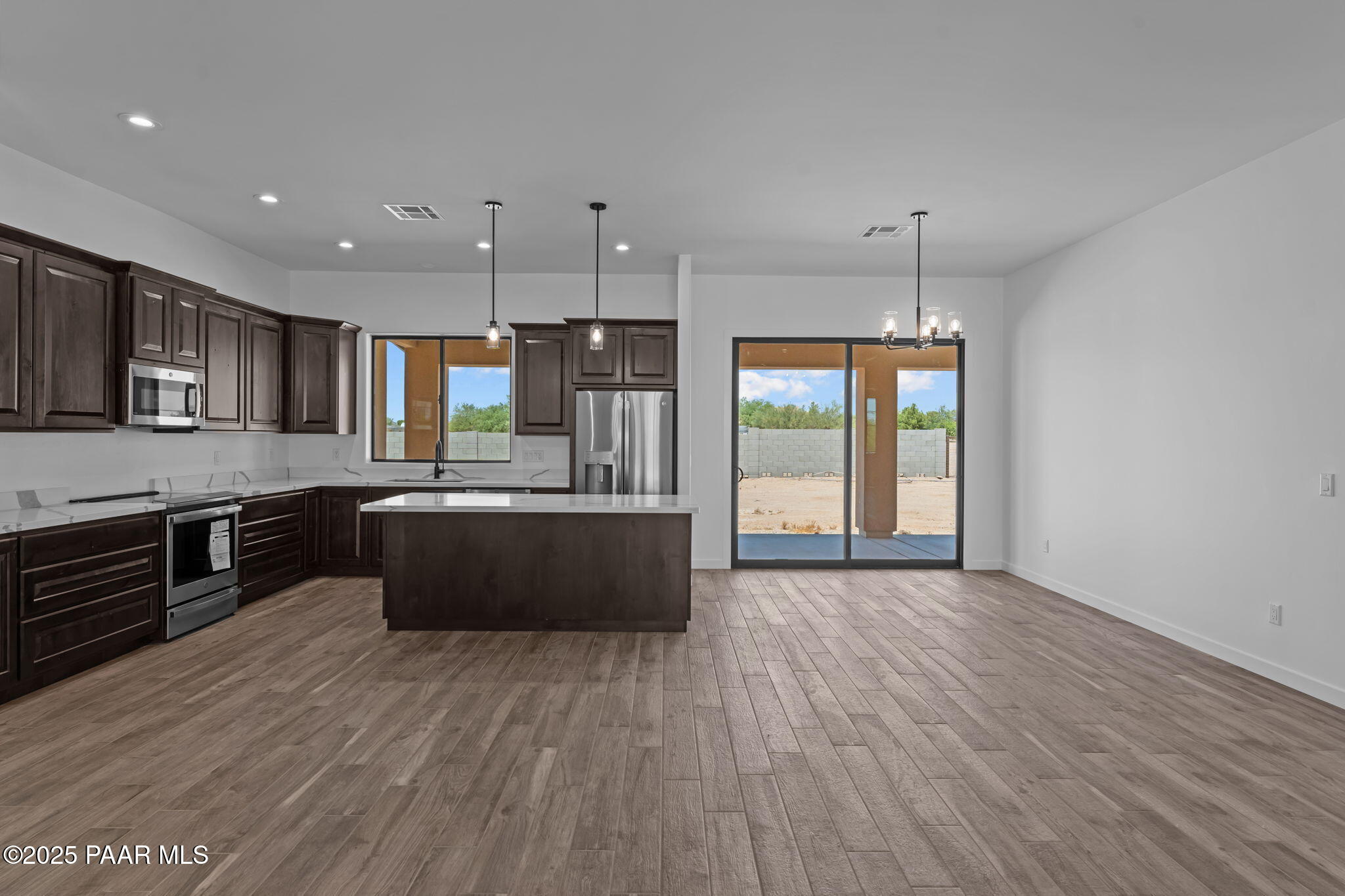 21032 West Skinner Road Wittmann, AZ 85361 - Photo 11 of 34 a large kitchen with stainless steel appliances kitchen island granite countertop a large counter top and wooden floors