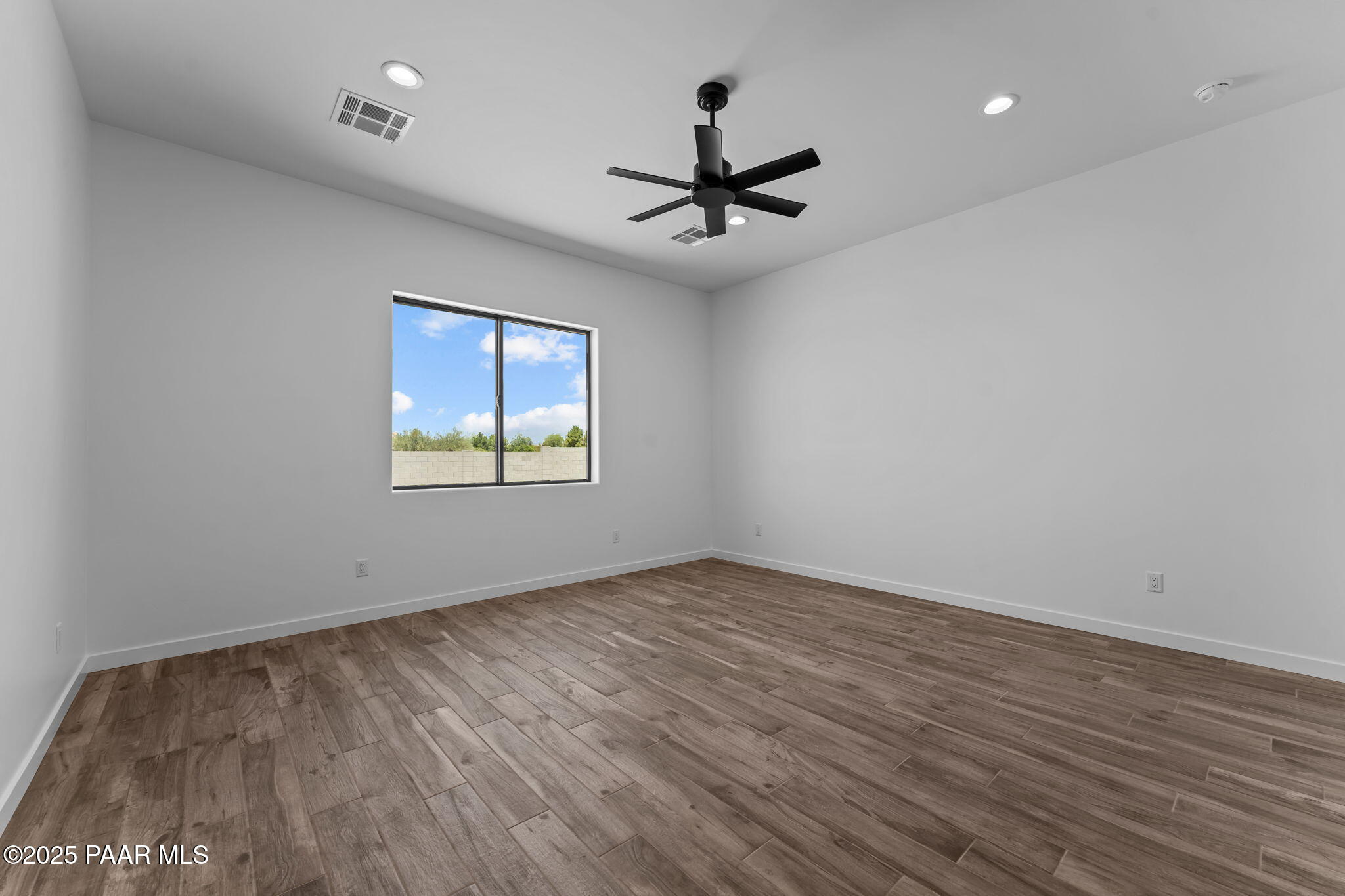 21032 West Skinner Road Wittmann, AZ 85361 - Photo 22 of 34 an empty room with wooden floor ceiling fan and windows
