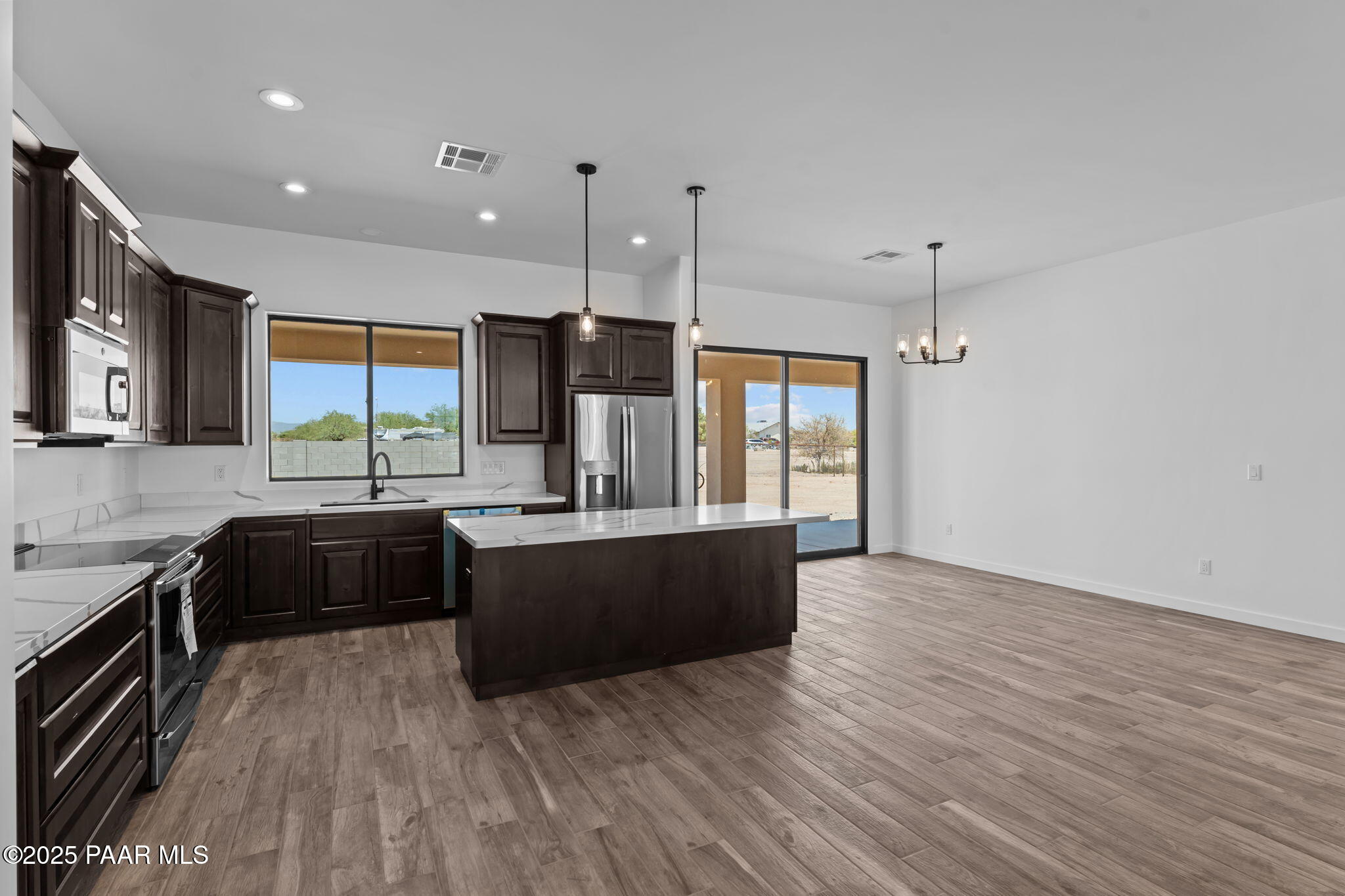 21032 West Skinner Road Wittmann, AZ 85361 - Photo 10 of 34 a large kitchen with stainless steel appliances granite countertop a stove and a wooden floors