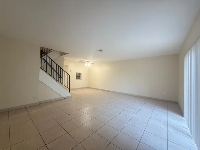 a view of an empty room with chandelier fan