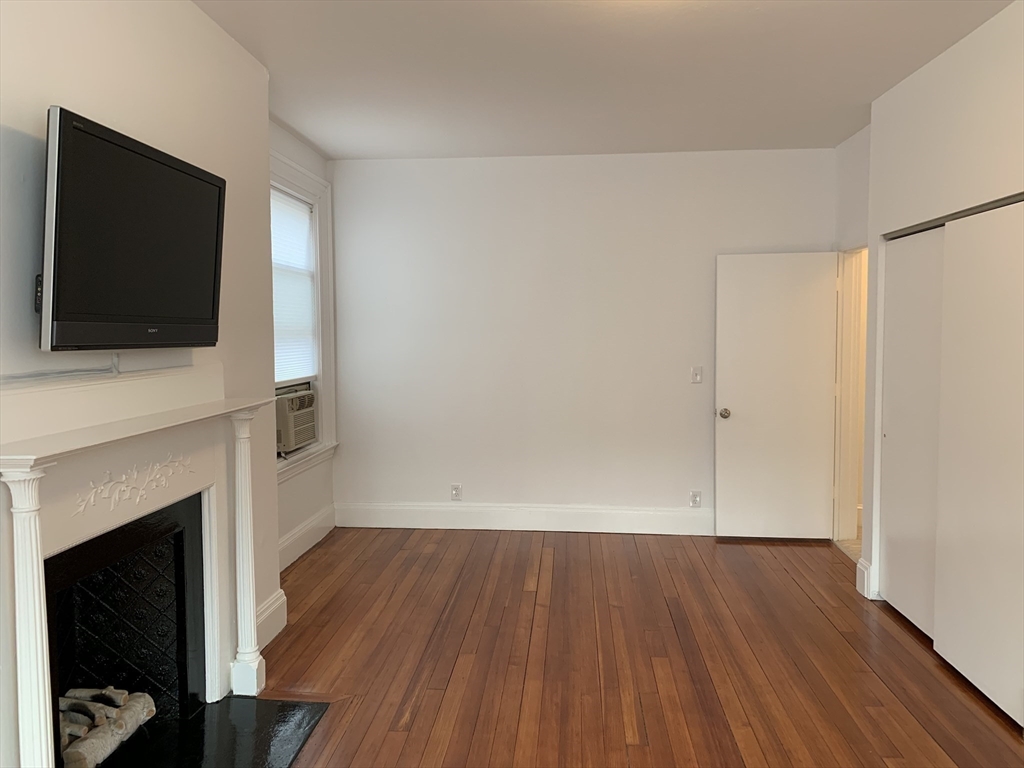 1064 Beacon Street, Unit 9 Brookline, MA 02446 - Photo 8 of 19 a view of a livingroom with wooden floor and a fireplace
