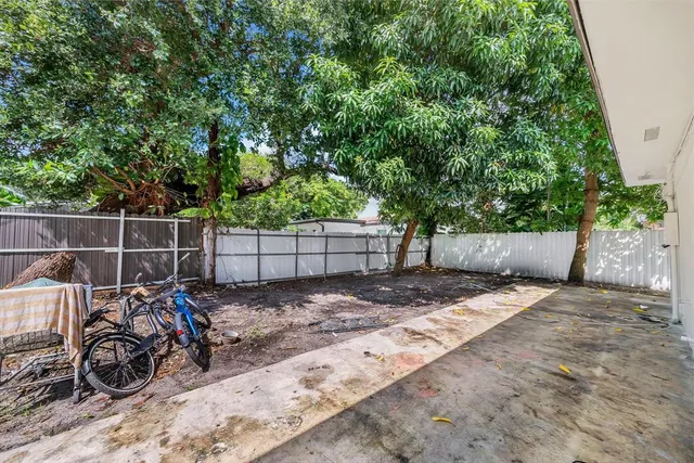 a backyard of a house with potted plants and large tree