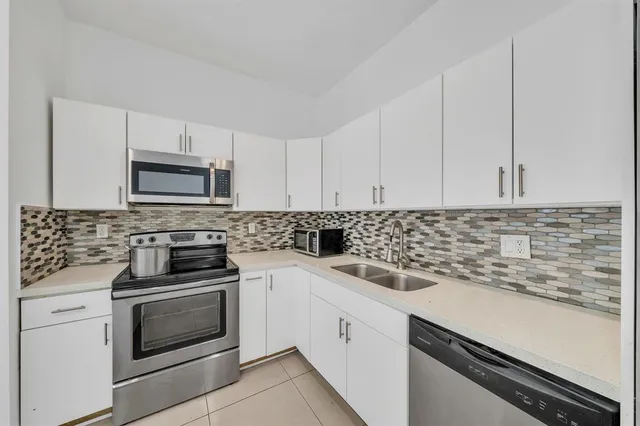 a kitchen with white cabinets stainless steel appliances and sink