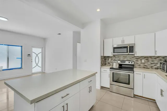 a kitchen with granite countertop white cabinets and stainless steel appliances