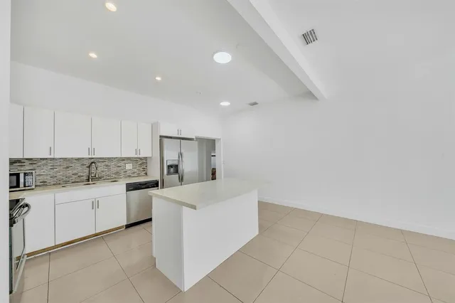 a large kitchen with granite countertop a sink and white cabinets