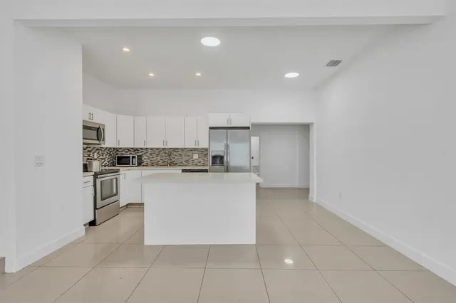 a kitchen with a refrigerator and white cabinets