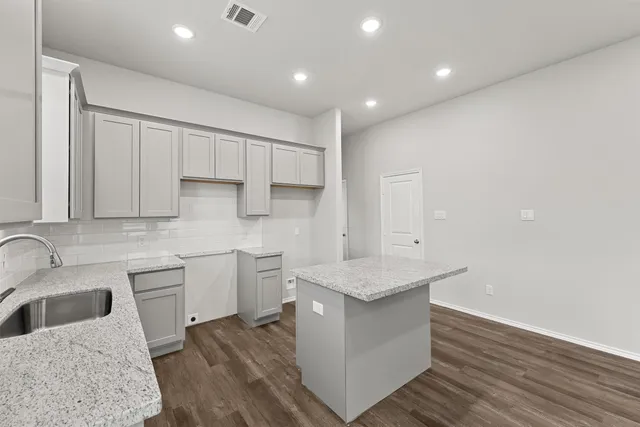 a kitchen with a sink dishwasher a stove and white cabinets with wooden floor