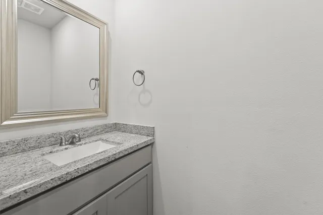 a bathroom with a granite countertop sink and a mirror