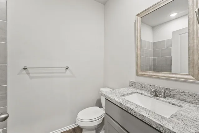 a bathroom with a granite countertop sink a toilet and a mirror