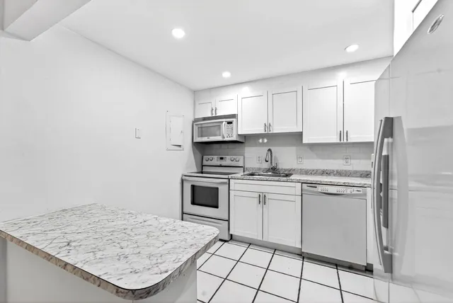 a kitchen with kitchen island granite countertop a stove sink and microwave